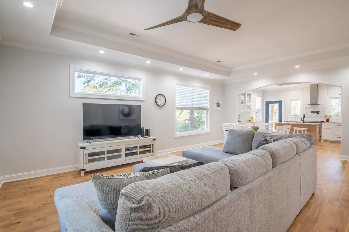A cozy living space with a comfortable sofa, television, dining area, and large windows that flood the room with natural light. The room blends relaxation and entertainment zones, featuring hardwood floors and stylish decor for an inviting feel.