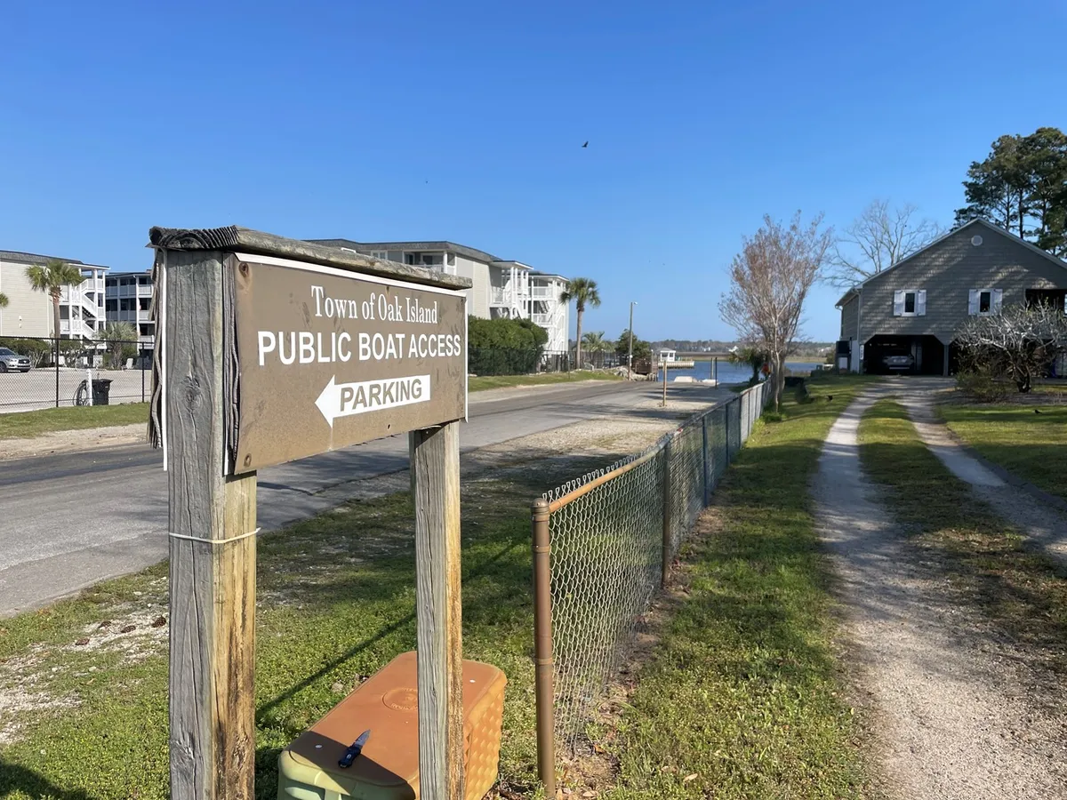 A clear view of the public boat access area, featuring visible signage for boat and parking access, nearby buildings, and a well-maintained pathway leading toward the water. The surroundings suggest easy accessibility and a relaxed, welcoming atmosphere, ideal for families and boating enthusiasts.